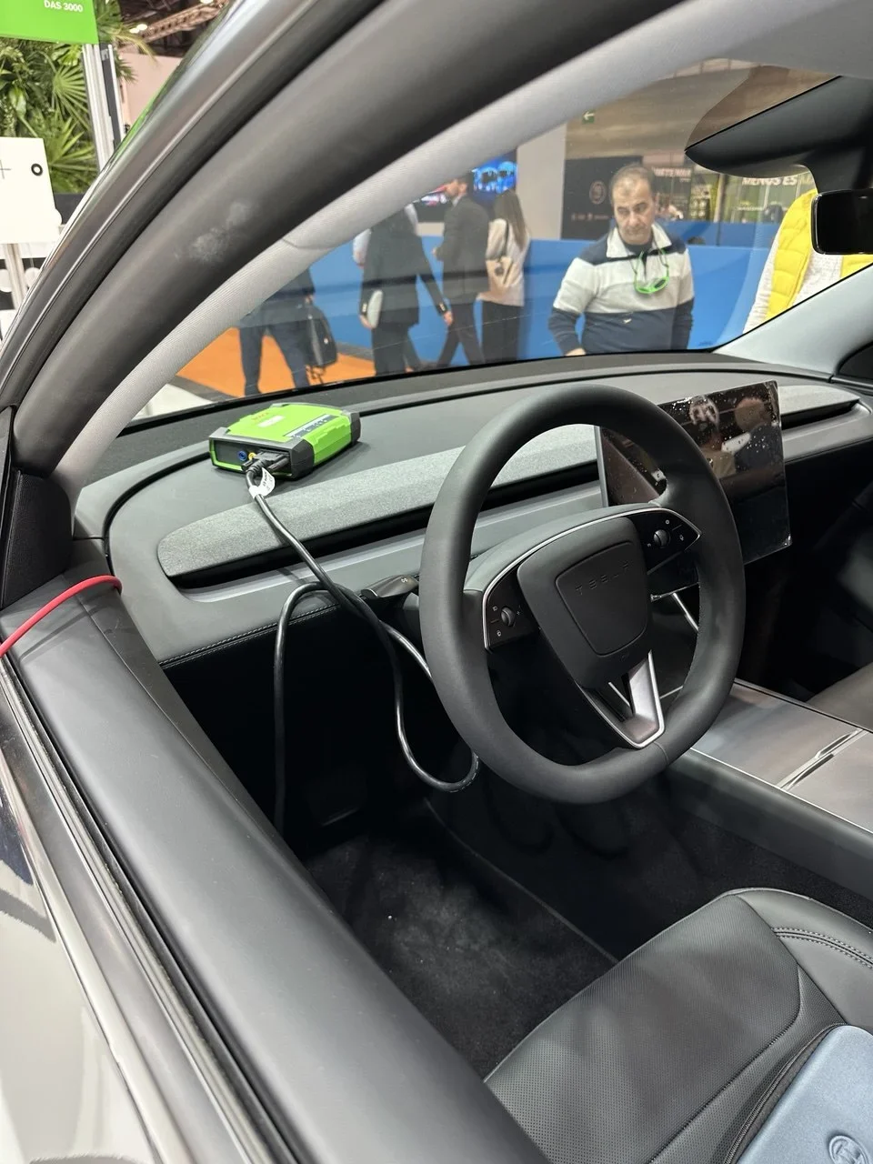 Vista del interior del automóvil que muestra un tablero minimalista con un volante y un dispositivo verde en el tablero.