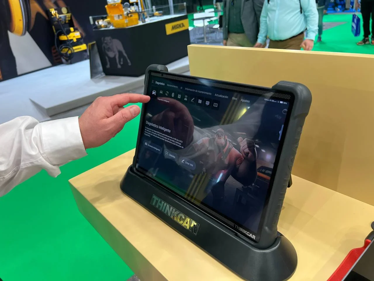 Una persona utiliza una tableta con pantalla táctil denominada THINKCAR en un stand de exhibición de tecnología.