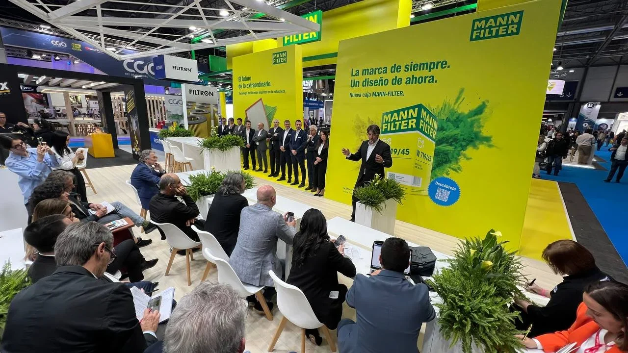 Un orador se presenta ante una audiencia en un stand de Mann Filter durante una feria comercial o un evento empresarial.