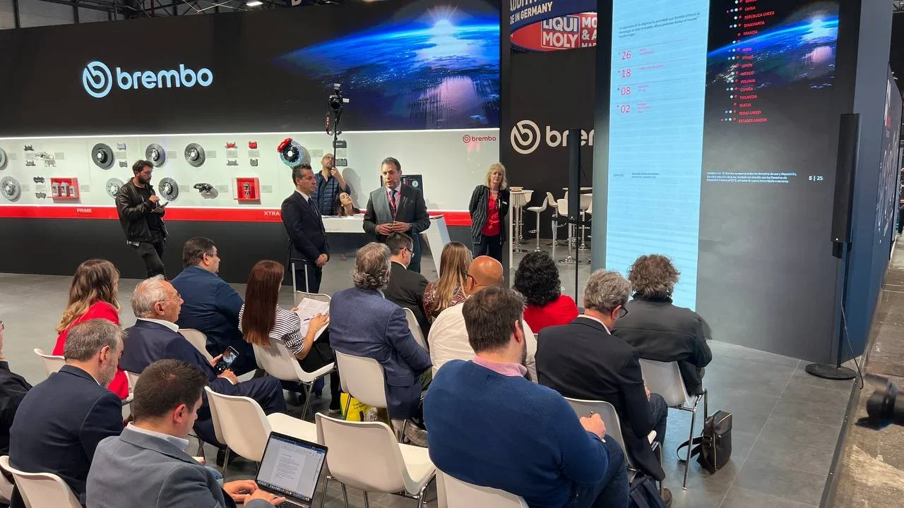 Un grupo de personas asiste a una presentación en un stand de Brembo en una sala de exposiciones.