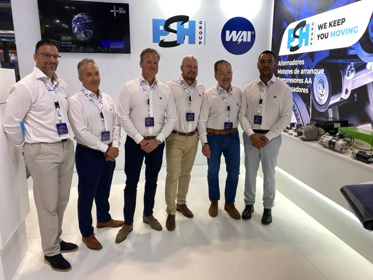 Seis hombres con camisas blancas posan en un stand de exhibición con la marca PSH Group y WAI al fondo, capturados en directo durante el segundo día de Motortec 2025.