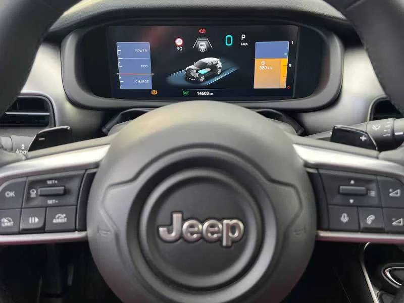 Primer plano de un volante de Jeep con una pantalla de tablero digital que muestra información sobre el vehículo y la energía.