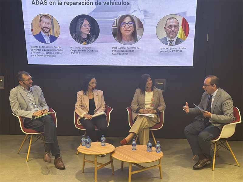 Cuatro panelistas se sientan y hablan en el escenario de un evento de reparación de vehículos, hablando de Sistemas ADAS, con una diapositiva de presentación detrás de ellos.