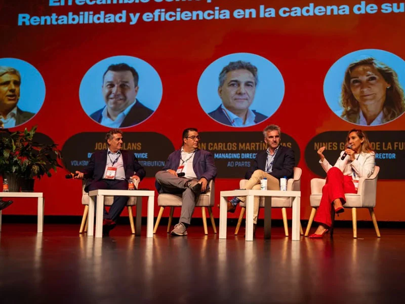 Cinco panelistas se sientan en el escenario para debatir sobre la eficiencia en la cadena de suministro, con un telón de fondo rojo y naranja a sus espaldas.