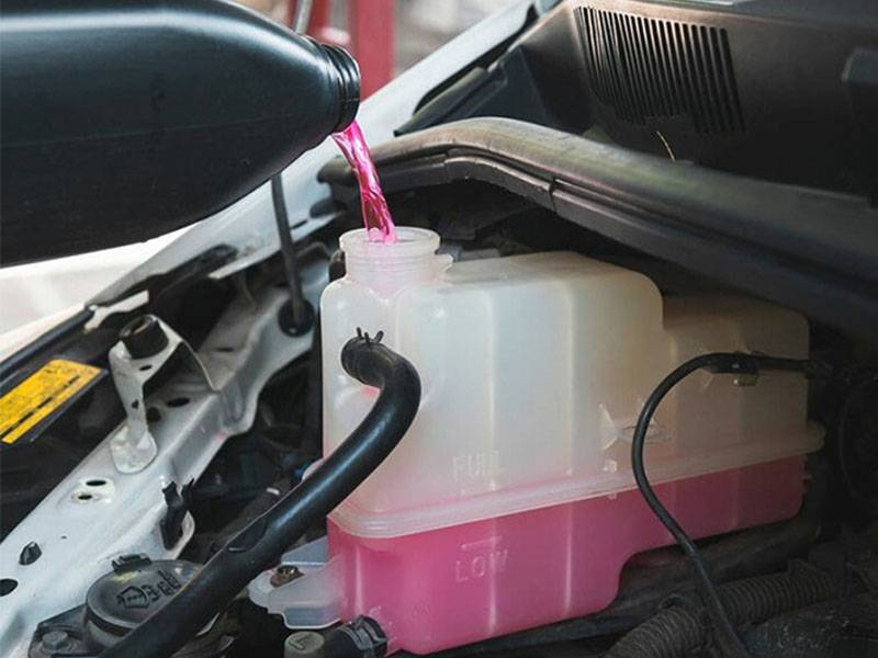 Pink coolant, uno de los productos térmicos recomendados, se vierte en el depósito del motor para preparar el vehículo para el invierno.