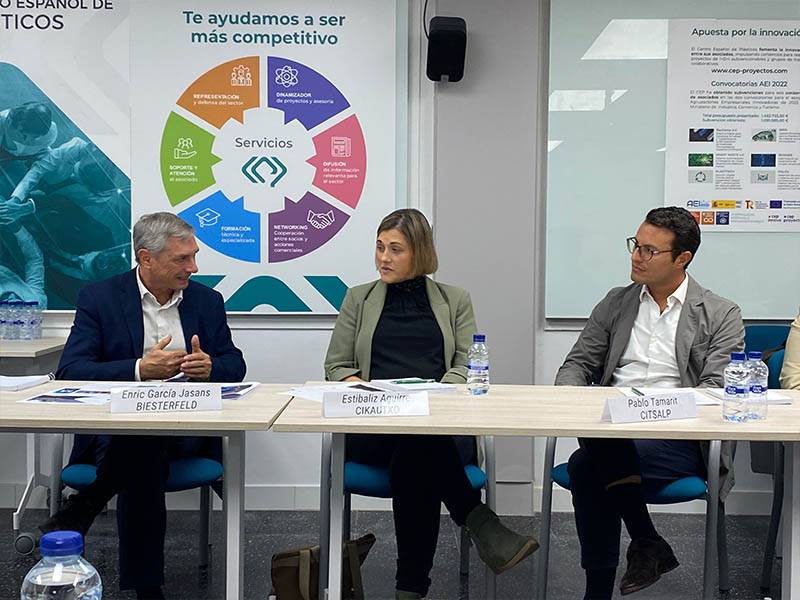 Tres personas sentadas a una mesa de conferencias en una moderna sala de reuniones de oficina, debaten sobre los plásticos reciclados y su impacto en el sector del automóvil en el marco de la normativa europea ELV.
