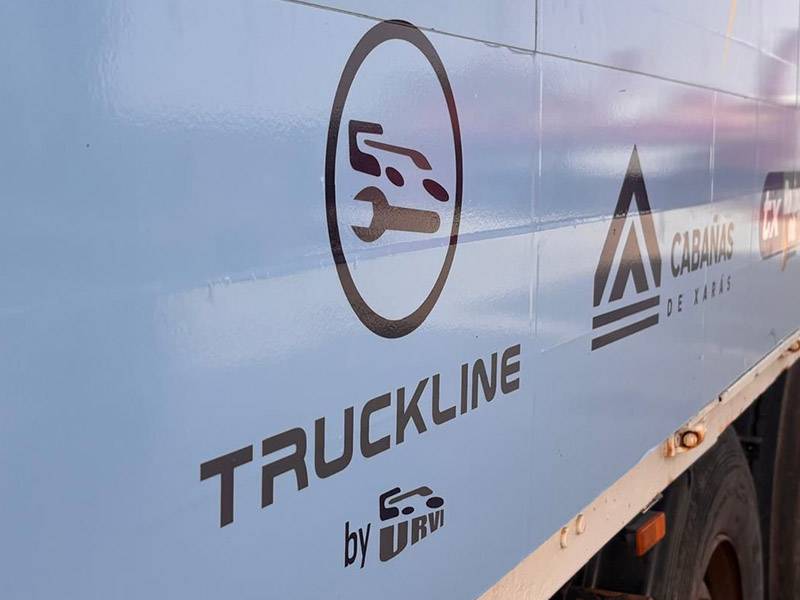 Primer plano de un camión azul con logotipos y texto en negro, entre ellos "TRUCKLINE" y un icono de camión estilizado, ideal para compañías del sector inspiradas en el recorrido del Dakar.