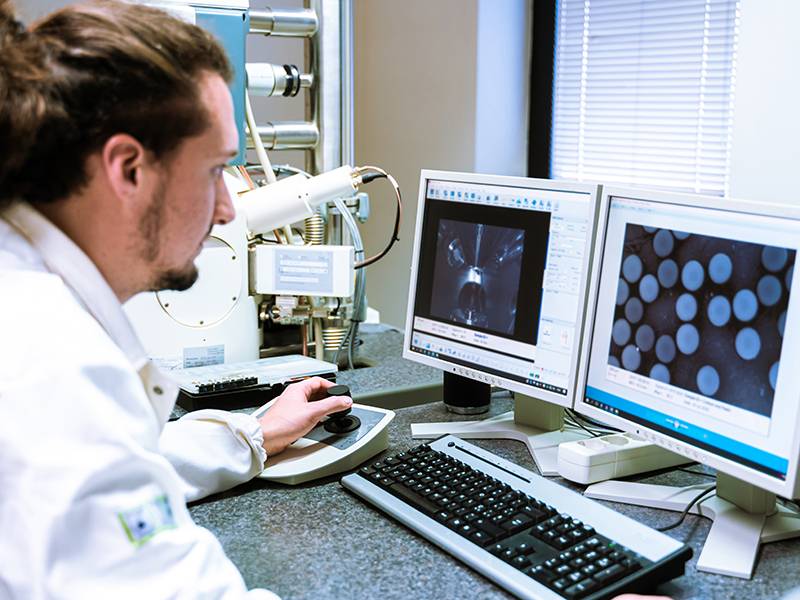 Un científico analiza imágenes microscópicas en dos monitores de ordenador en un laboratorio.