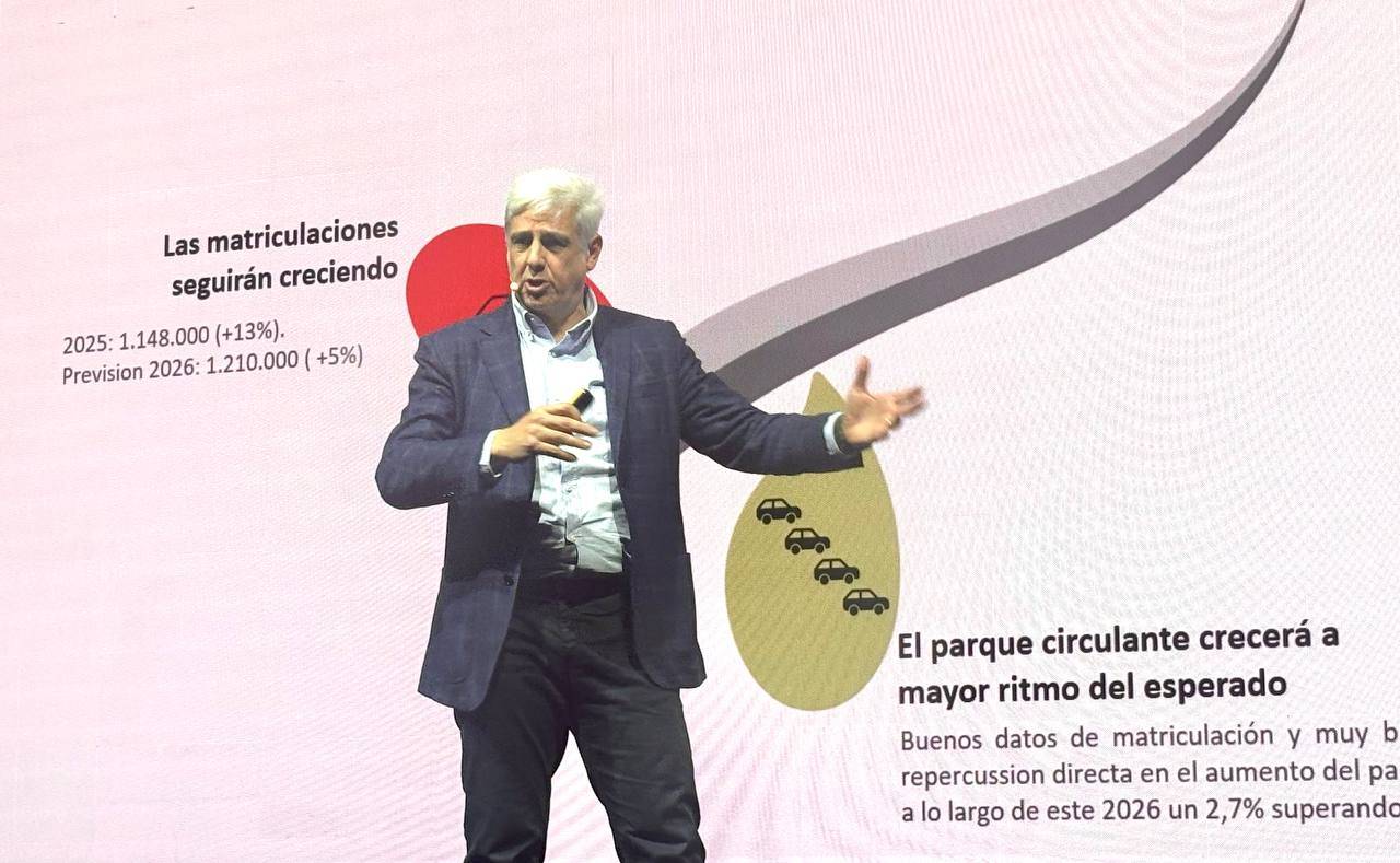 Hombre haciendo una presentación delante de una pantalla con estadísticas de matriculación de coches y un gráfico de crecimiento en español.