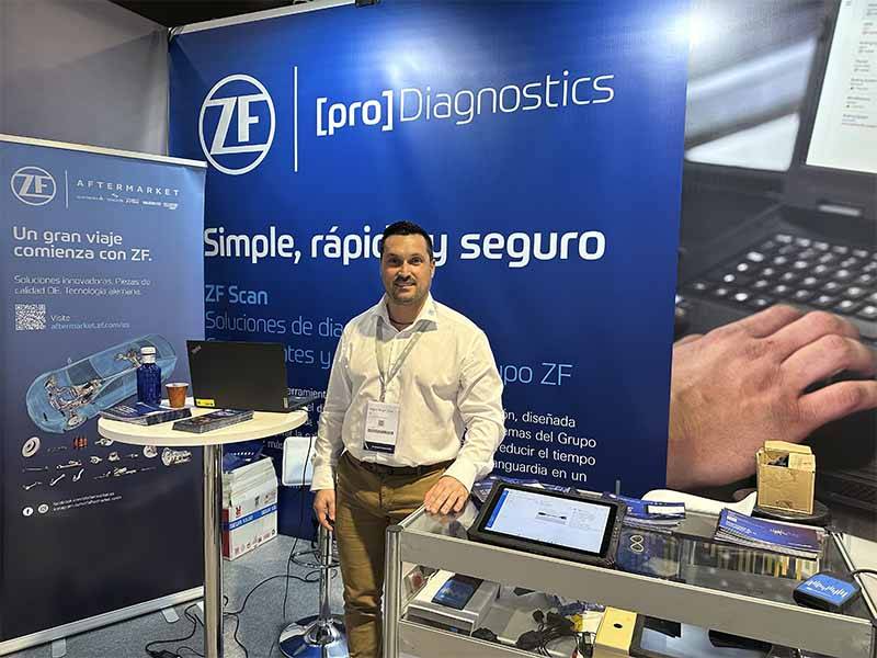 Un hombre se encuentra en un stand de ZF Diagnostics con folletos, dispositivos y un expositor promocional azul detrás de él, destacando el éxito de asistencia en Balance de Equipia 2026.
