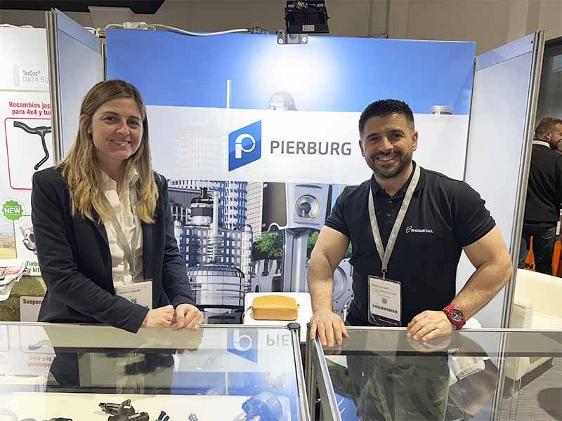 Dos personas sonríen en un stand de Pierburg, que muestra su oferta y Balance de Equipia 2026, con vitrinas y un telón de fondo azul y blanco detrás de ellos.