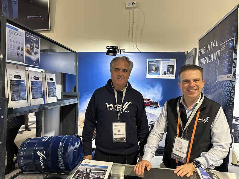 Dos hombres en un stand de Wolf Lubricants durante Equipia 2026, de pie detrás de un mostrador con folletos y productos, contribuyendo al éxito de asistencia en el evento.