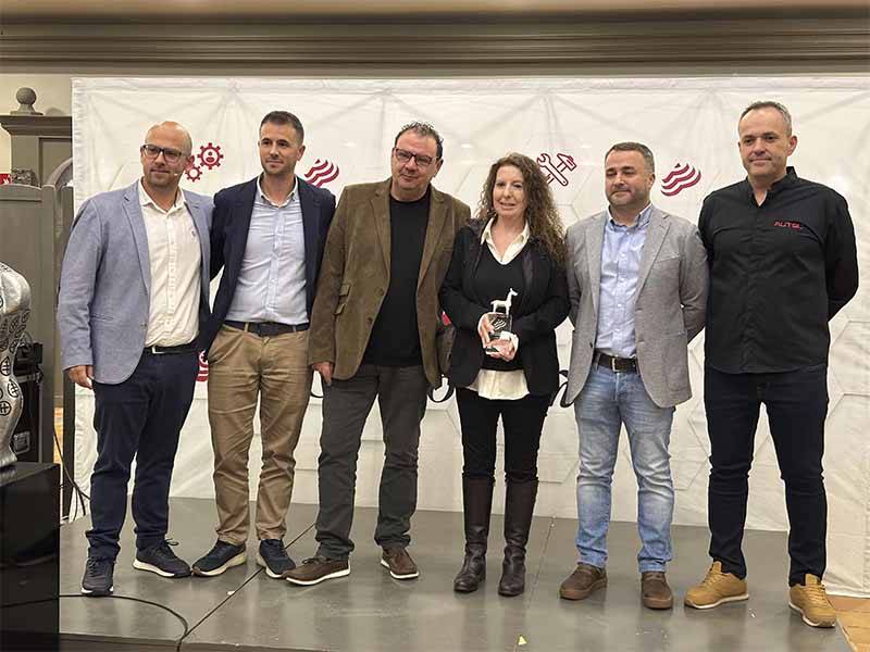 Seis personas permanecen juntas en el interior; una mujer en el centro sostiene un trofeo que celebra el Balance de Equipia 2026, y todos sonríen a la cámara.