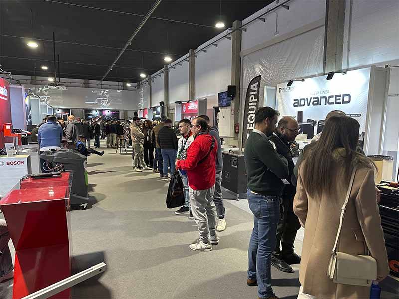 La gente hace cola y pasea por una exposición cubierta en la que se exhiben diversos equipos y pancartas, destacando la asistencia Equipia así como la oferta exclusiva Equipia.