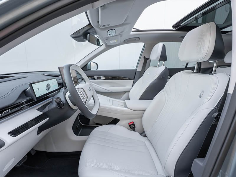 Interior de coche moderno con asientos de cuero blanco, salpicadero digital y techo solar, visto desde el lado del conductor del Geely E5 eléctrico.