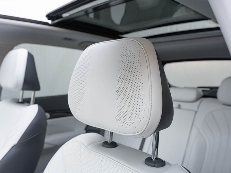 Primer plano de un reposacabezas de cuero blanco con detalles perforados en el interior de un moderno Geely Starray EM-i, con techo solar y detalles premium.