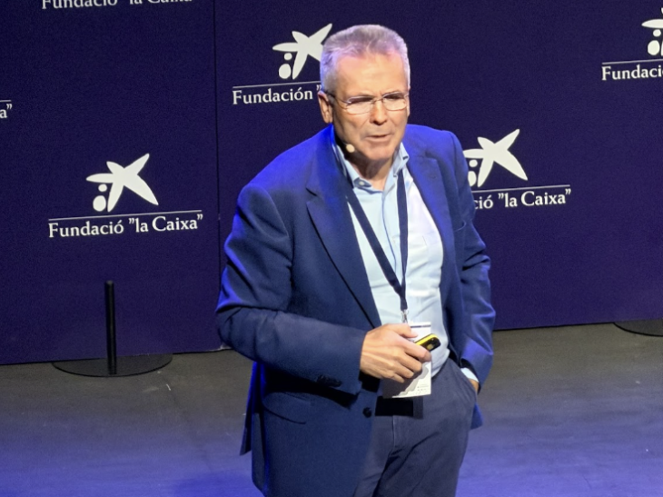 Un hombre con traje azul habla en el escenario de un acto de la Fundación "la Caixa".