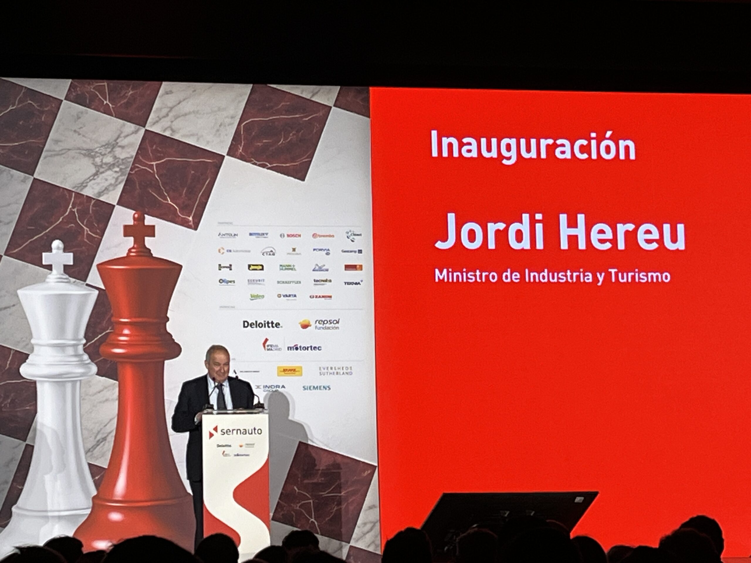 Un hombre habla en un podio junto a una pantalla en la que se lee "Jordi Hereu, Ministro de Industria y Turismo.