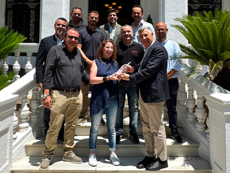 Un grupo de Grupo Peña posa en unas escaleras al aire libre; dos personas, en el centro de la primera fila, sonríen mientras sostienen un premio de cristal de los Premios Cervatillo, que reconocen la excelencia en el servicio posventa.