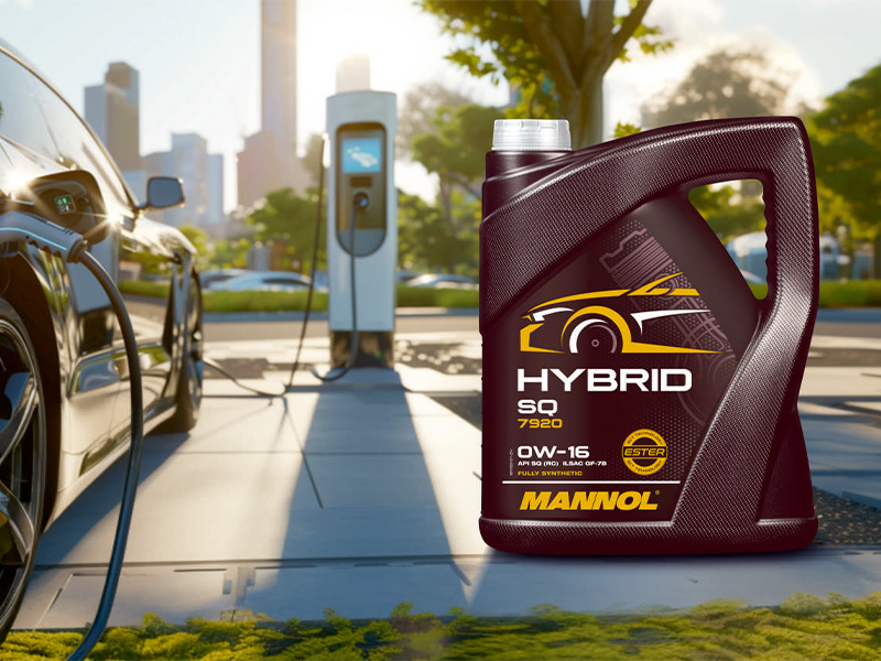 Una botella de aceite de motor Mannol Hybrid se encuentra frente a una estación de recarga de coches eléctricos al aire libre.