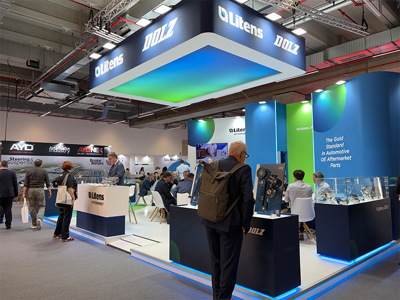 Los visitantes se acercan a un stand de feria muy bien iluminado en el que se exponen piezas de automóvil, con la imagen de marca en azul y verde de Litens Aftermarket en la feria Automechanika de Fráncfort.