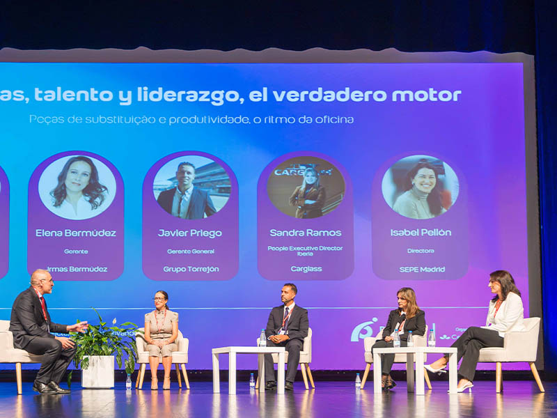 Cinco profesionales se sientan en el escenario durante una mesa redonda, con los perfiles de los ponentes proyectados en una pantalla situada detrás de ellos.