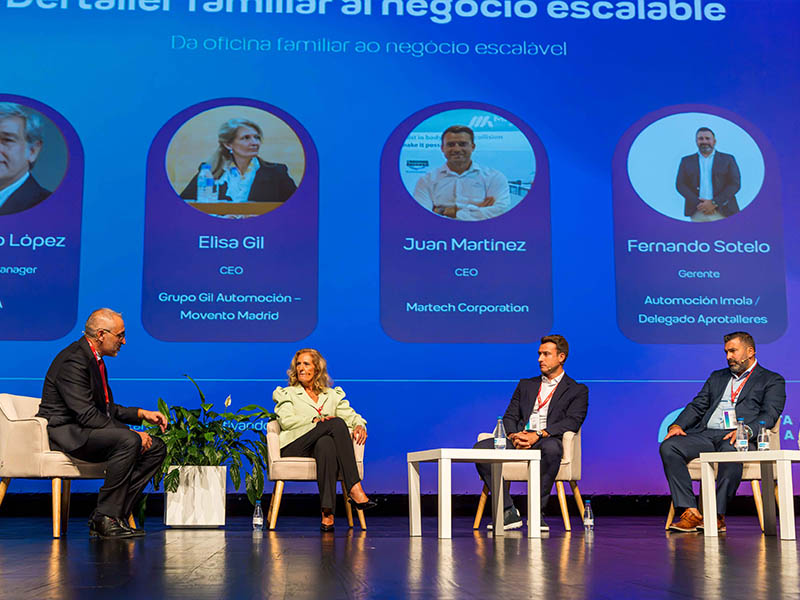 Cuatro personas vestidas con ropa de trabajo hablan en el escenario, con sus perfiles profesionales proyectados en una pantalla situada detrás de ellas.