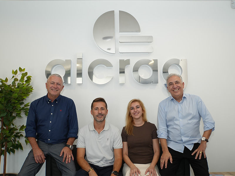 Cuatro personas posan delante del logotipo de una oficina de Aicrag, lo que pone de manifiesto su crecimiento.