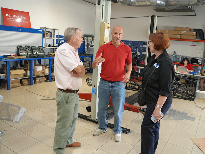 Tres personas debaten sobre la evolución del sector del automóvil en un taller.