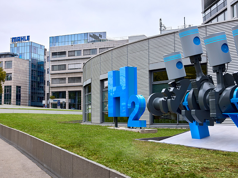Una gran escultura azul de H2 y un componente mecánico de motor en la zona de transición del taller de Mahle.