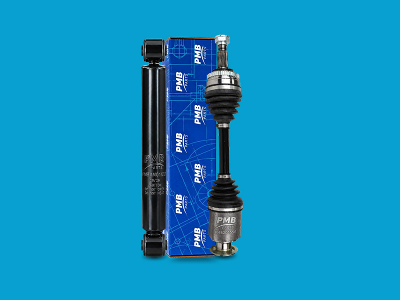 Un amortiguador y un semieje están colocados delante de una caja azul de PMB Parts, un componente técnico.